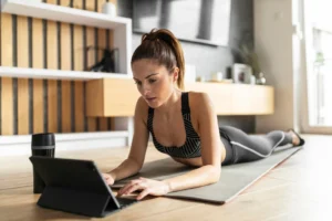 Mulher trabalhando em seu notebook enquanto descansa de um exercício no chão.