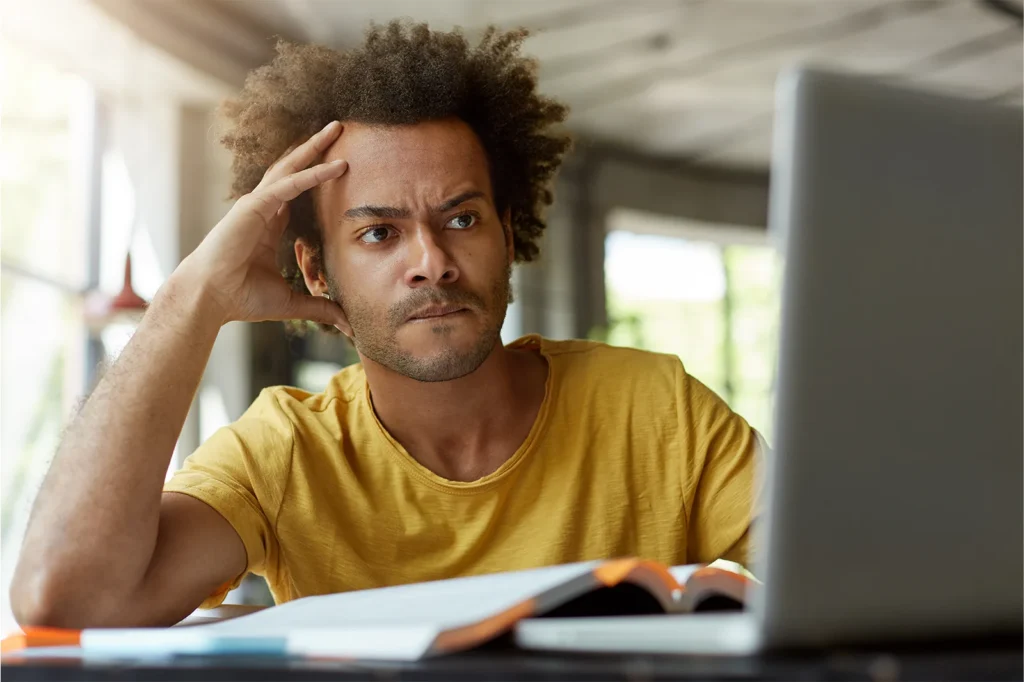 Jovem tentando descobrir como gerenciar o estresse diante do trabalho frente aos estudos.